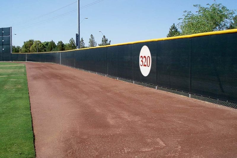 Dark windscreen on an outfield fence behind the warning track